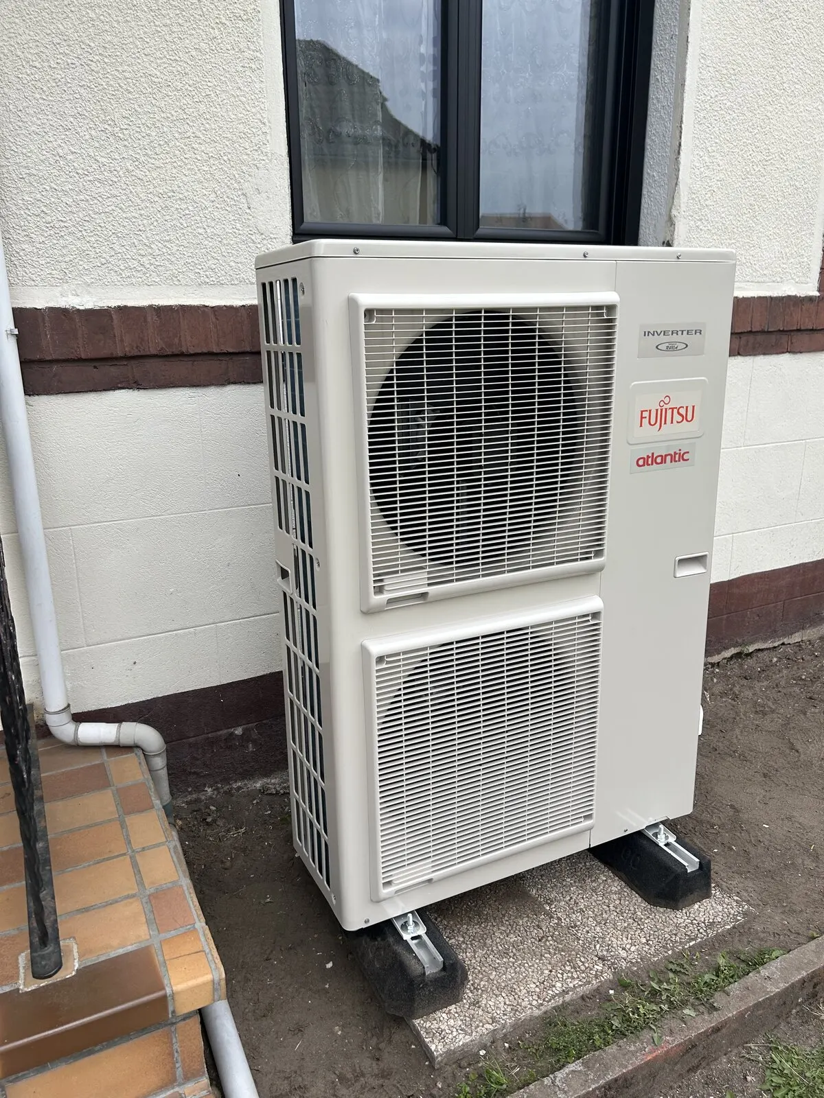 Unité extérieure de pompe à chaleur air-eau posée contre la façade d’une maison de Saint-Étienne-du-Rouvray